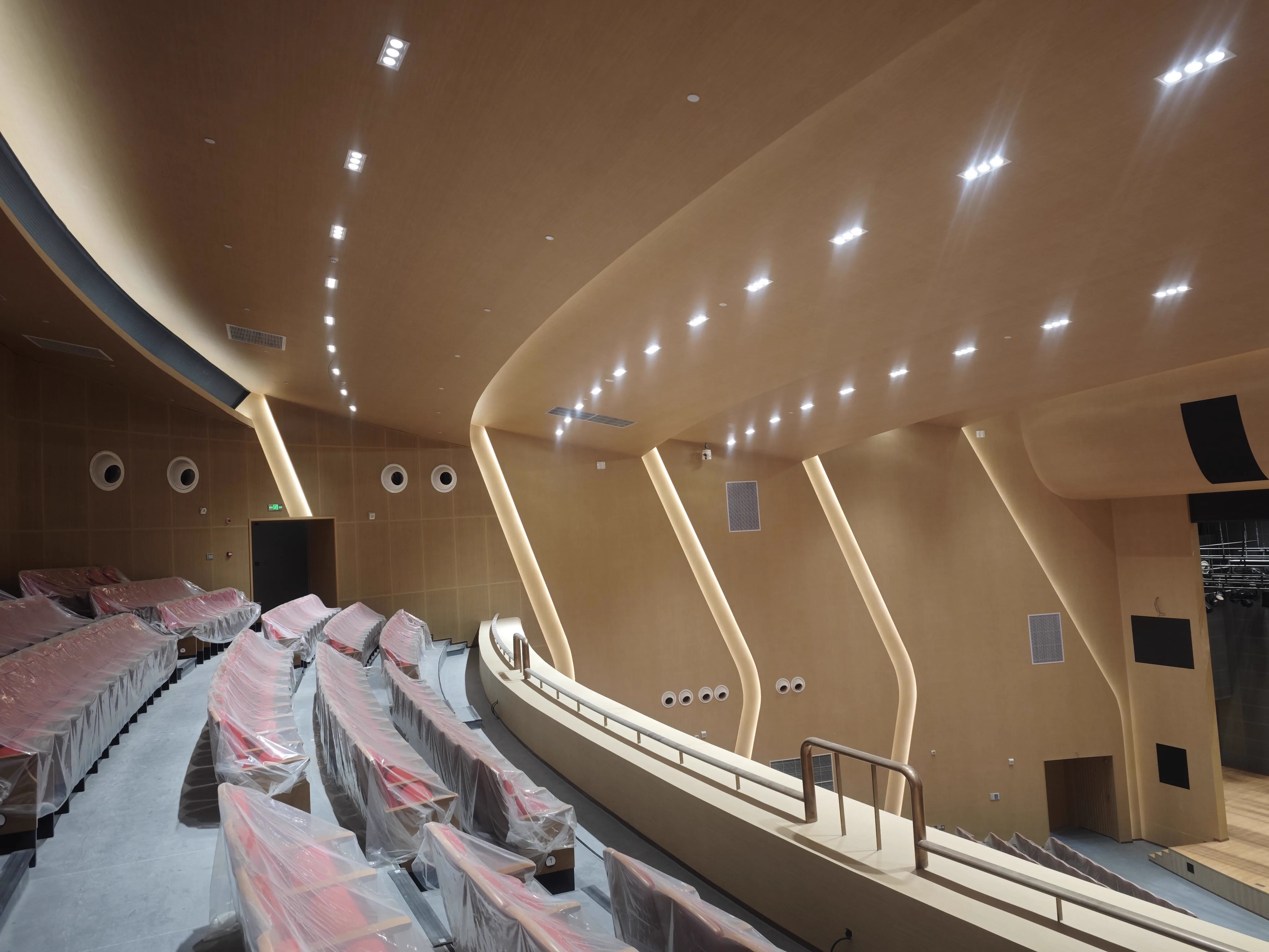 Upper balcony auditorium view showing seating rake, side-wall acoustic geometry, and stage opening