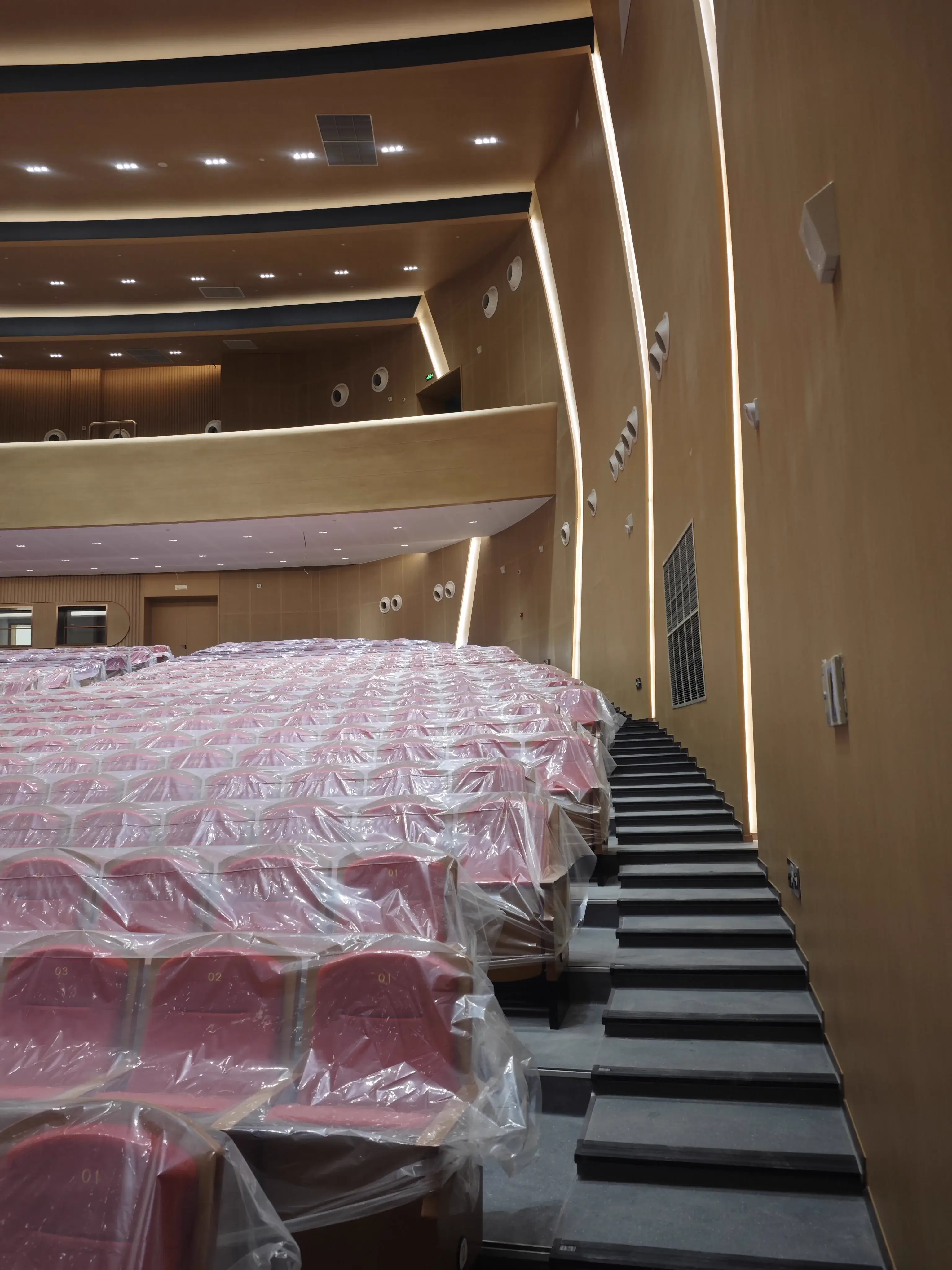 Auditorium side aisle and covered red seats beside acoustic wall panels