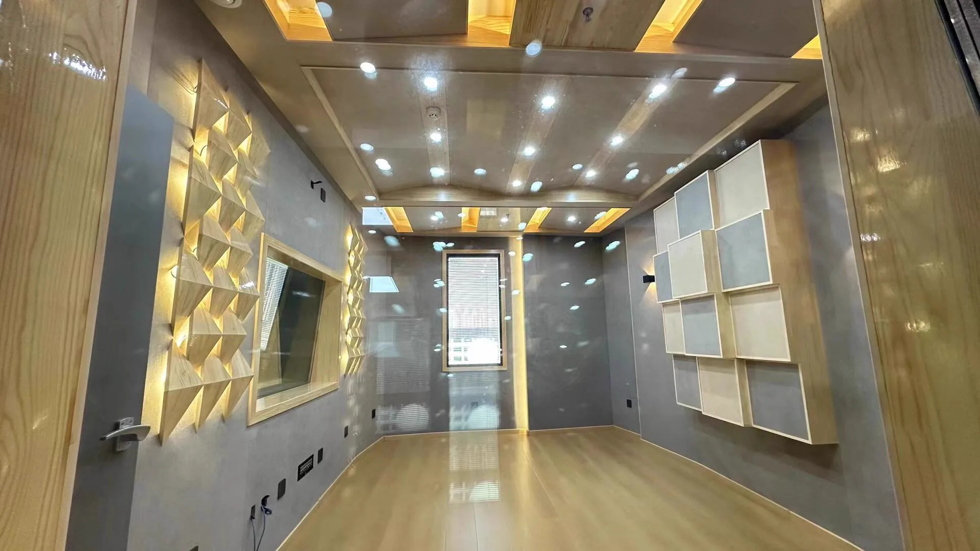 Empty recording room viewed through glass with observation window and staggered wall acoustic modules