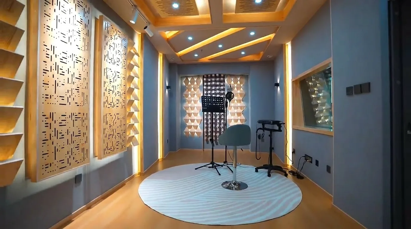 Finished live room with condenser microphone, music stand, round rug, high stool, and acoustic diffuser walls