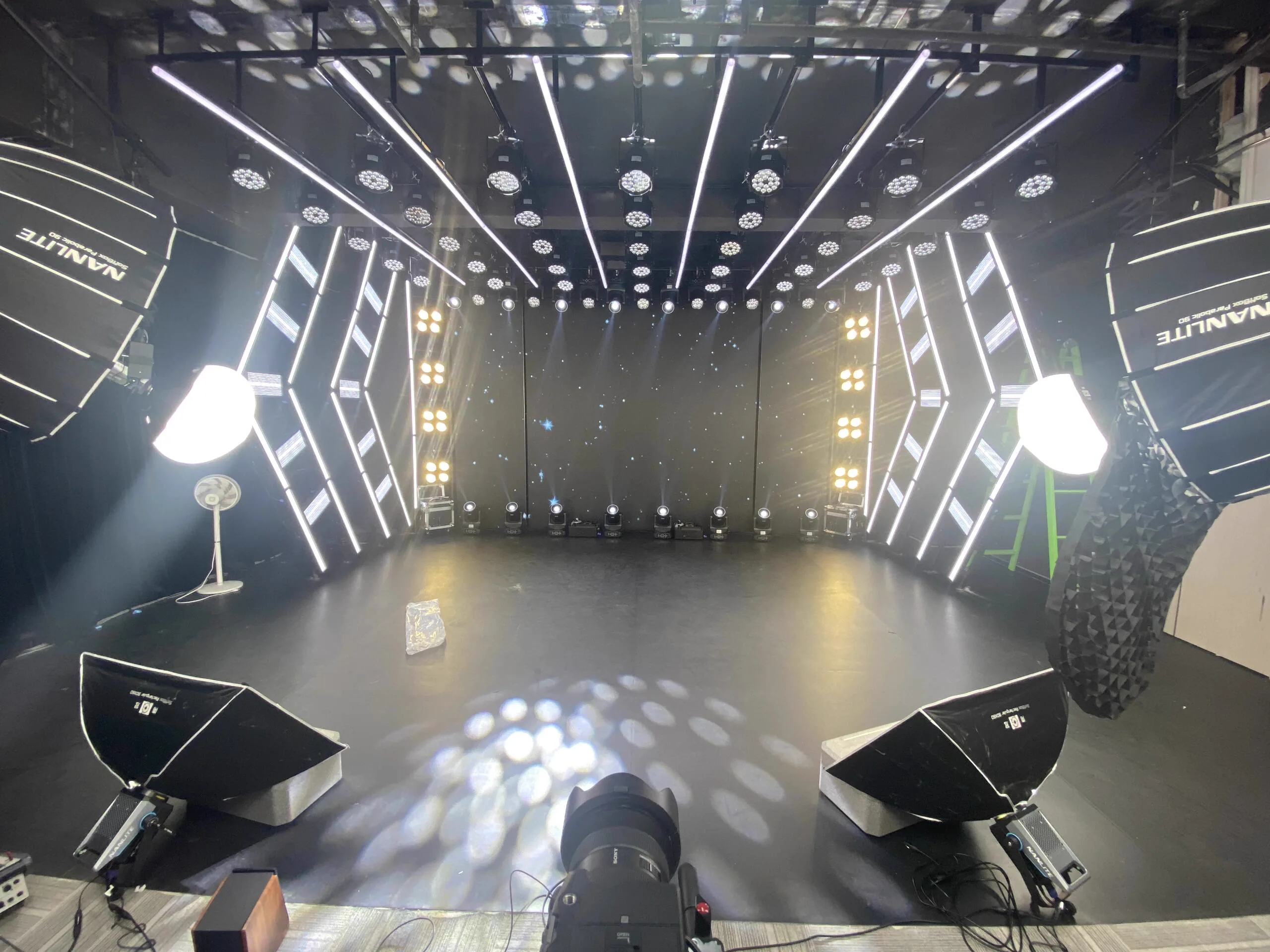 Full-matrix broadcast studio wide view with symmetrical truss lighting and LED backdrop